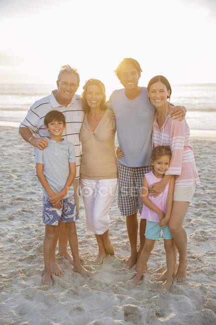 Familia sonriendo juntos en la playa - foto de stock