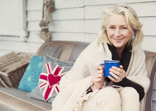 Ritratto sorridente anziana che beve caffè sul divano del patio — Foto stock