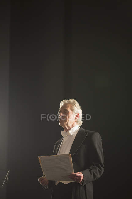 Спокойный дирижер оркестра держит ноты с закрытыми глазами — стоковое фото