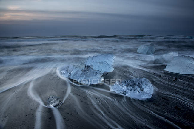 Lunga esposizione di ghiaccio sulla spiaggia fredda e tempestosa dell'oceano, Jokulsarlon, Islanda — Foto stock
