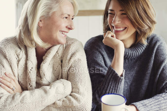 Lachende Mutter und Tochter im Pullover beim Kaffeetrinken — Stockfoto