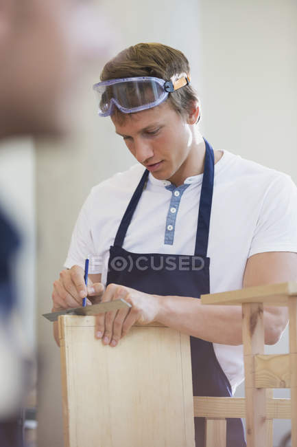 Tischler misst Holz in Werkstatt — Stockfoto