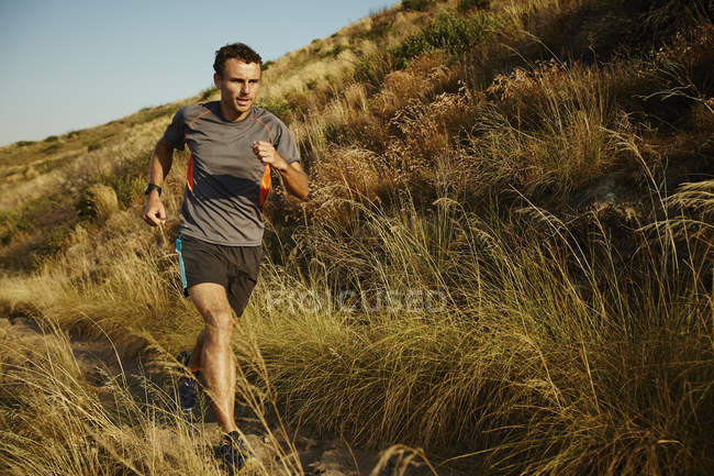 Mann läuft auf Wanderweg durch hohes Gras — Stockfoto