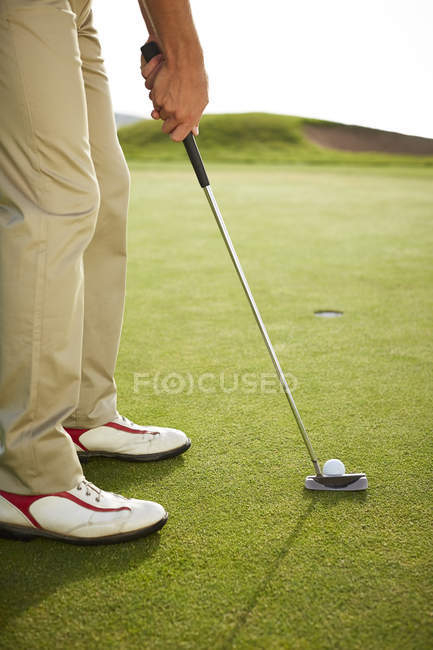 Imagen recortada del hombre que se prepara para putt en el campo de golf - foto de stock