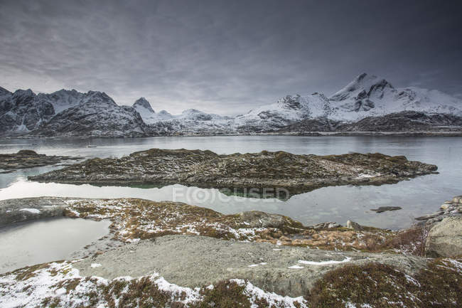 Schneebedecktes Gebirge hinter zerklüfteter Bucht, Sund, erhabenen Inseln, Norwegen — Stockfoto