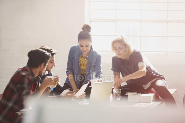 Creative young business people brainstorming at laptop in sunny office — Stock Photo
