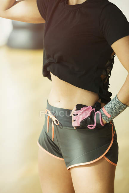 Mujer de sección media en forma con pantalones cortos en el gimnasio - foto de stock