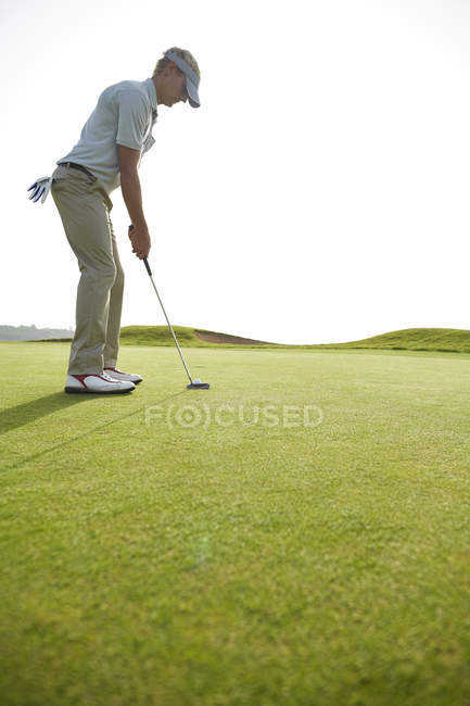 Vista lateral del hombre poniendo en campo de golf - foto de stock