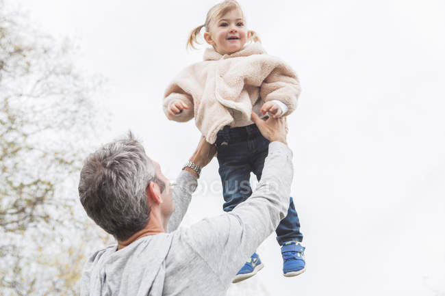 Отец поднимает ребенка дочь над головой — стоковое фото