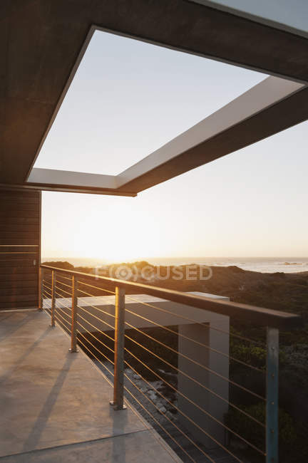 Балкон современного дома с видом на океан на закате — стоковое фото