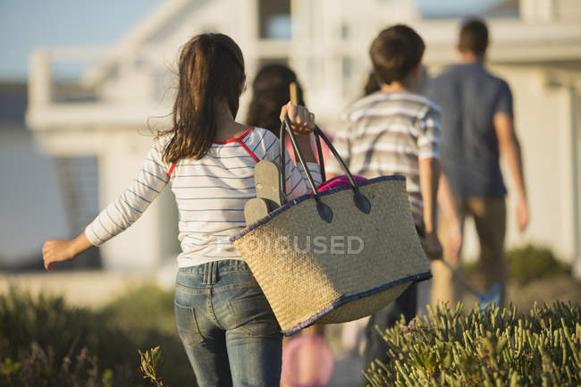 Menina com saco de praia seguinte família — Fotografia de Stock