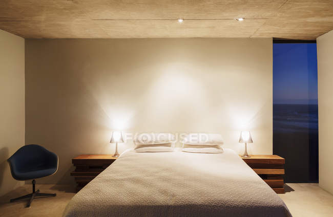 Lâmpadas iluminadas e cama no quarto moderno — Fotografia de Stock
