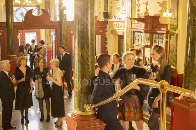 Gente bien vestida bebiendo champán en el vestíbulo del teatro - foto de stock