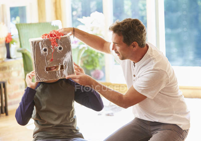 Father placing robot mask on son — Stock Photo