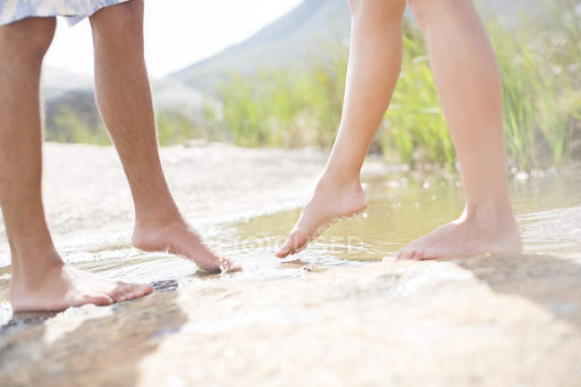 Casal mergulhando pés na lagoa rural — Fotografia de Stock