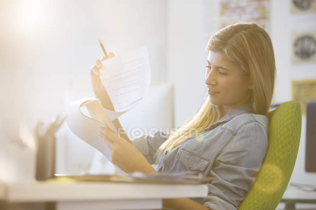 Donna d'affari che legge alla scrivania in ufficio — Foto stock