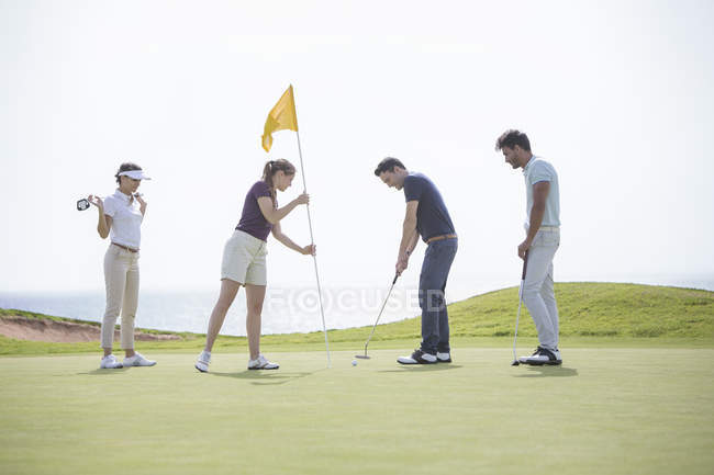 Caucasian friends putting on golf course — Stock Photo