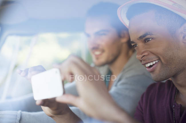 Los hombres que utilizan el teléfono de la cámara en coche - foto de stock