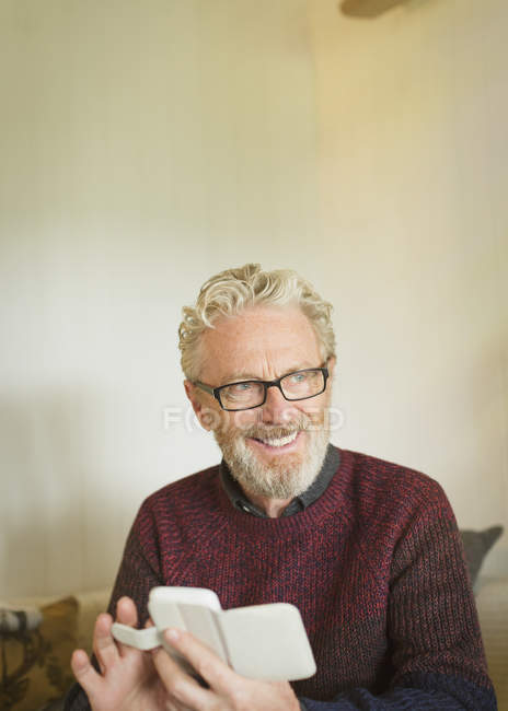 Uomo anziano sorridente che messaggia con il cellulare — Foto stock