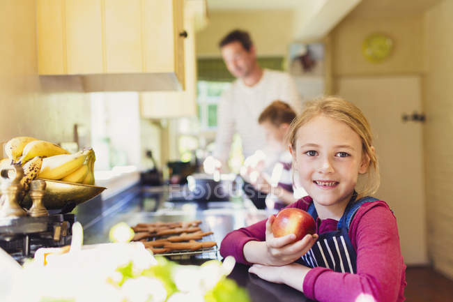 Portrait smiling girl eating apple in kitchen — Stock Photo