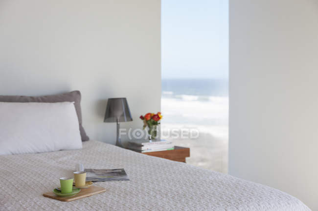 Tray with espresso cups on bed in bedroom with ocean view — Stock Photo