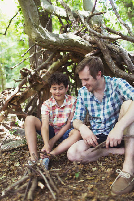 Отец и сын разводят маленький костер с палками в лесу — стоковое фото