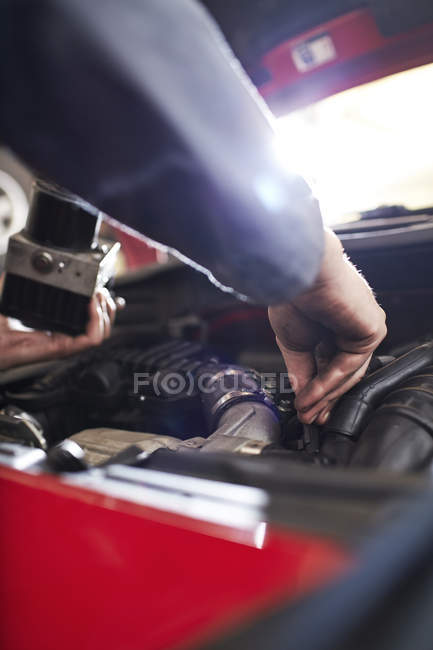 Fechar o braço mecânico atingindo no motor do carro — Fotografia de Stock