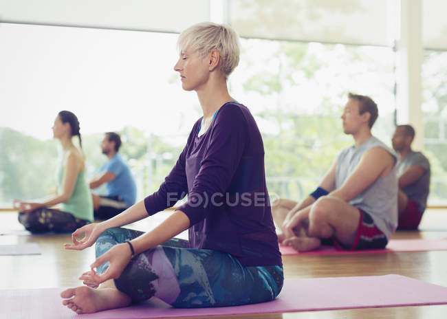 Mulher serena na posição de lótus na aula de ioga — Fotografia de Stock