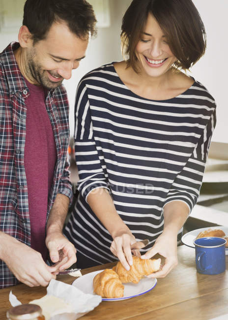 Couple buttering croissants indoors — Stock Photo