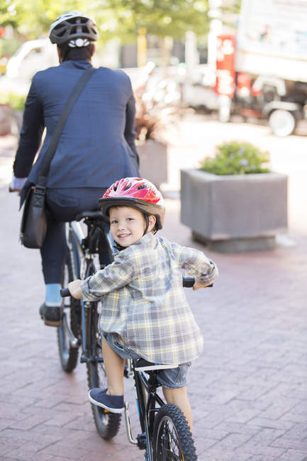 Retrato niño sonriente montar en bicicleta tándem con el padre empresario - foto de stock