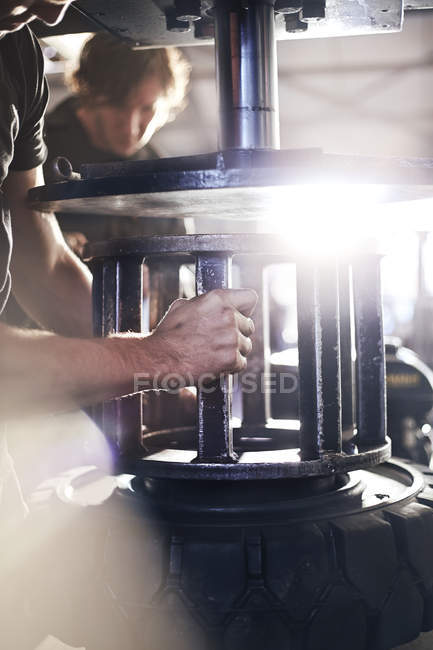 Mechanic using tire machinery in auto repair shop — Stock Photo
