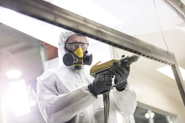 Trabajador en ropa de trabajo protectora usando taladro en fábrica - foto de stock