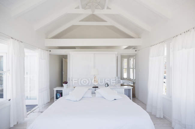 Rafters acima da cama no quarto branco — Fotografia de Stock