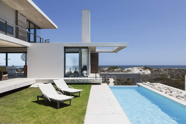 Стільці для відпочинку та басейн на колінах за межами сучасного будинку — стокове фото