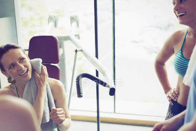 Lächelnde Frauen, die sich im Fitnessstudio ausruhen und unterhalten — Stockfoto