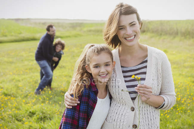 Портрет улыбающейся матери и дочери на лугу с полевыми цветами — стоковое фото