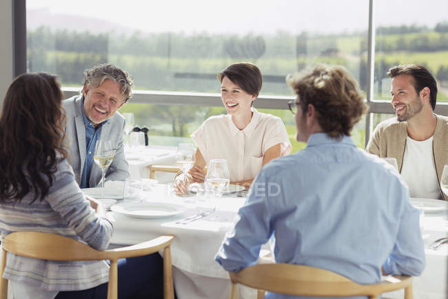 Freunde trinken Weißwein und unterhalten sich am sonnigen Restauranttisch — Stockfoto