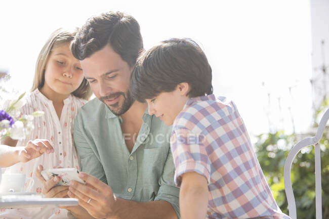 Батько і діти використовують мобільний телефон на відкритому повітрі — стокове фото