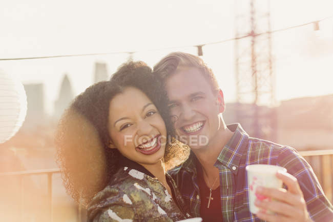 Портрет улыбающейся молодой пары, наслаждающейся вечеринкой на крыше — стоковое фото