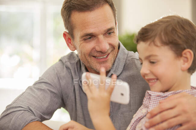 Pai e filho usando telefone celular — Fotografia de Stock
