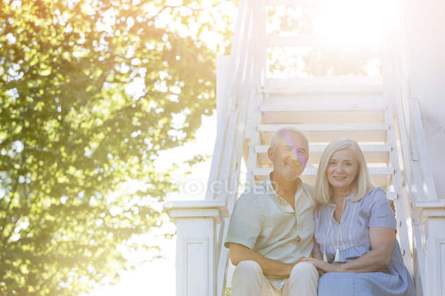 Portrait sourire couple âgé assis sur les escaliers d'été — Photo de stock