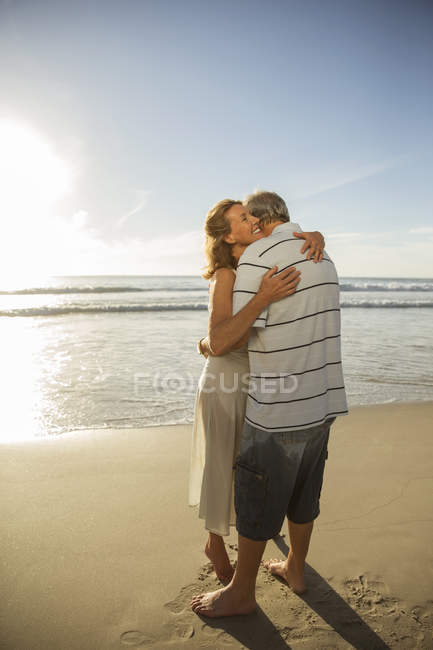 Older couple hugging on beach — Stock Photo