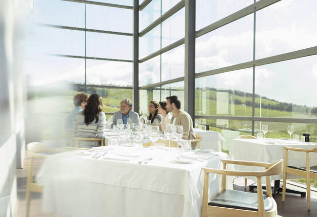 Freunde sitzen am Tisch im sonnigen Weingut-Speisesaal — Stockfoto