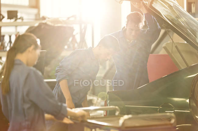 Mechanics looking inside trunk in auto repair shop — Stock Photo