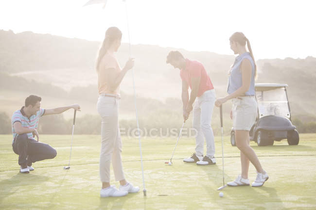 Caucasici giovani amici che giocano a golf sul campo — Foto stock