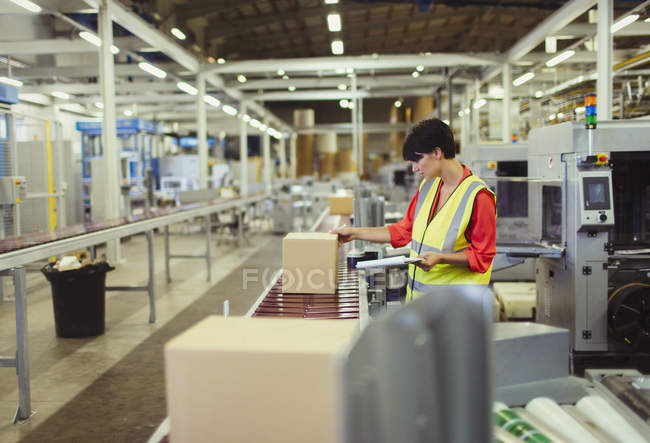 Працівник перевіряє картонні коробки на лінії виробництва конвеєрних поясів на заводі — стокове фото