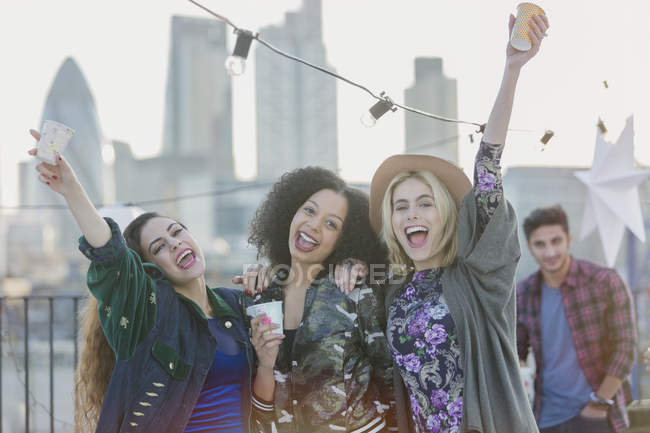 Портрет exuberant молодих жінок оплески і пити на даху партії — стокове фото