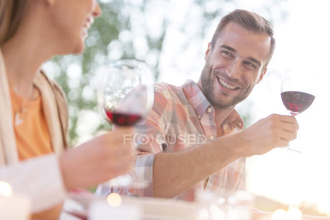 Sorridente giovane coppia bere vino rosso all'aperto — Foto stock