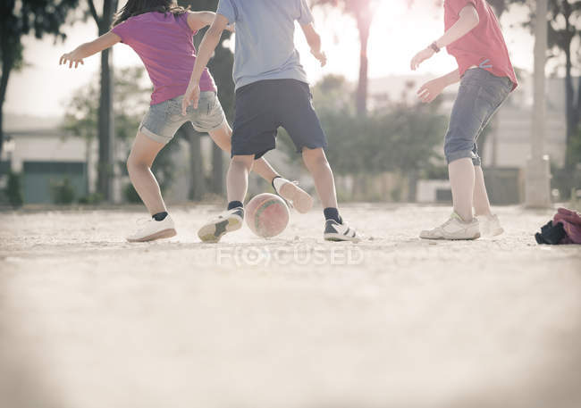 Bambini che giocano con pallone da calcio nella sabbia — Foto stock