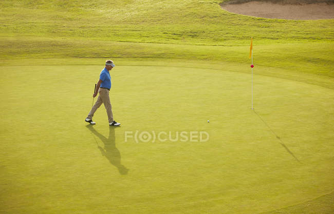 Вид сбоку на кавказца, идущего по полю для гольфа — стоковое фото